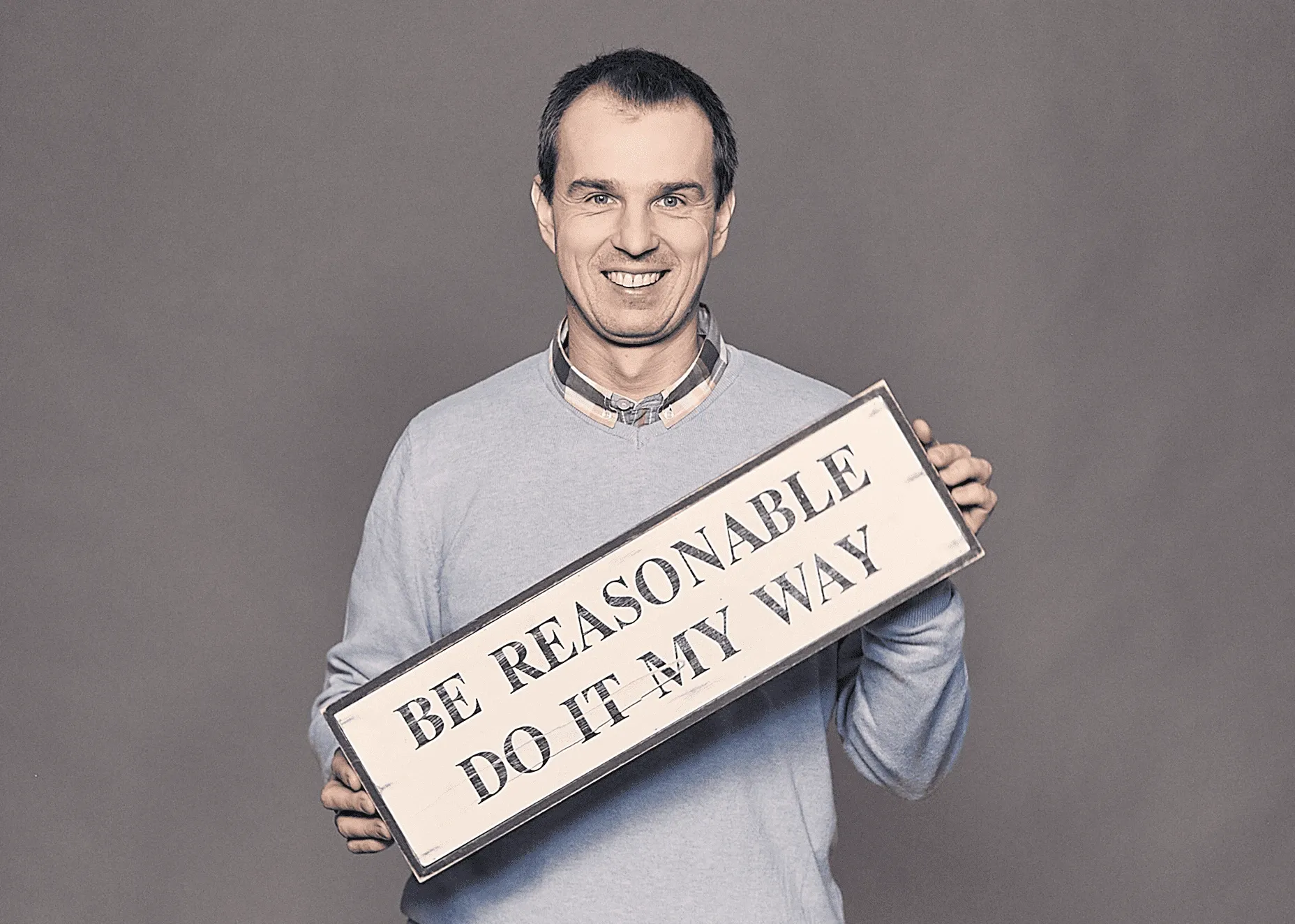 piotr żychliński holding board with text be reasonable do it my way